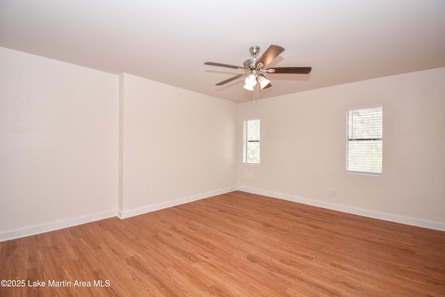 spare room featuring a ceiling fan, baseboards, and light wood-type flooring