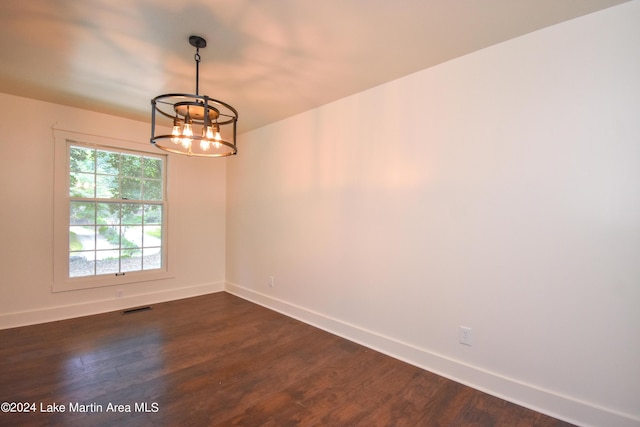 empty room featuring dark hardwood / wood-style flooring and a chandelier