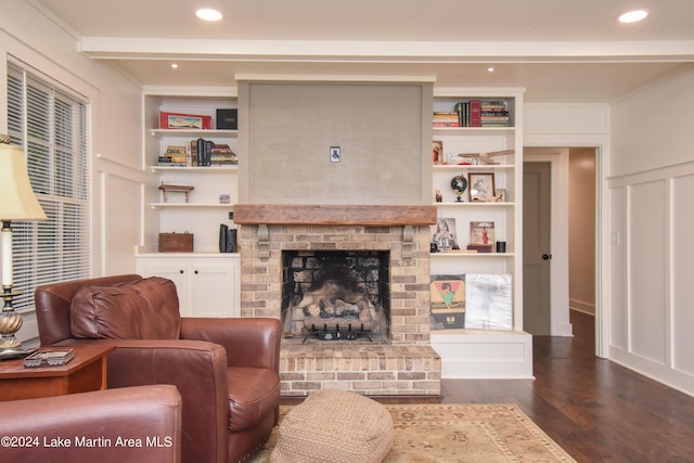 living room with beam ceiling, dark hardwood / wood-style flooring, ornamental molding, and a fireplace