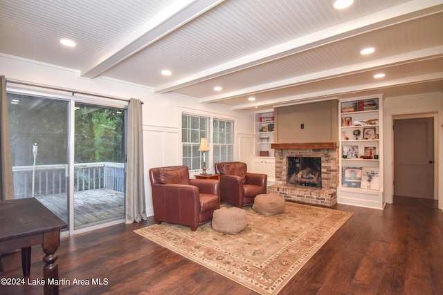 living room featuring beam ceiling, built in shelves, dark hardwood / wood-style flooring, and a brick fireplace