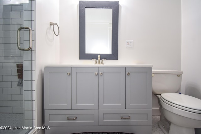 bathroom featuring tile patterned floors, a shower with door, vanity, and toilet