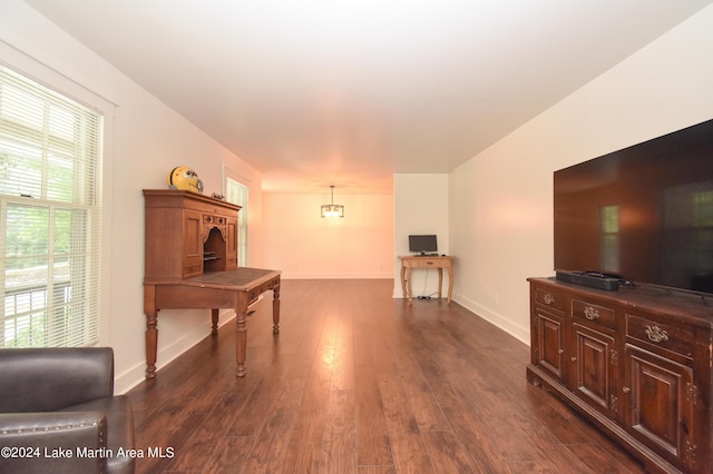 living room with dark hardwood / wood-style flooring, a healthy amount of sunlight, and a notable chandelier