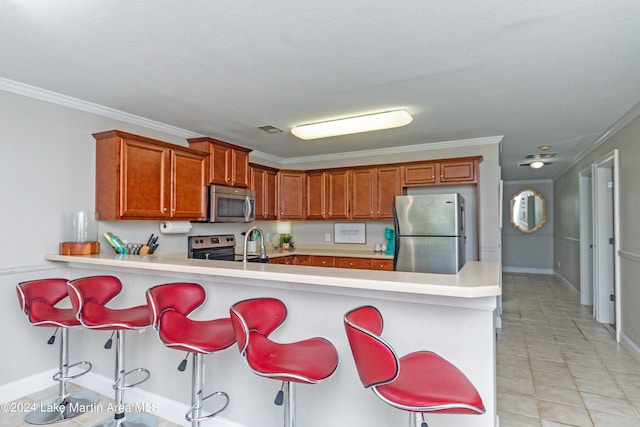 kitchen with a breakfast bar area, kitchen peninsula, ornamental molding, and appliances with stainless steel finishes