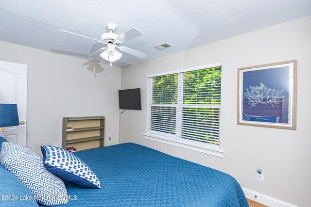 carpeted bedroom featuring ceiling fan and a textured ceiling