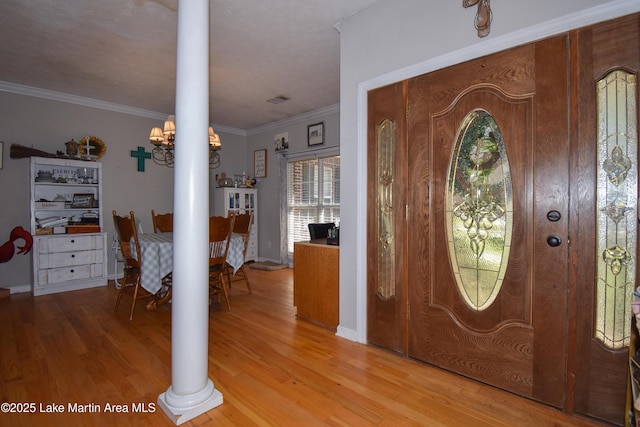 foyer entrance featuring visible vents, crown molding, light wood-type flooring, and ornate columns
