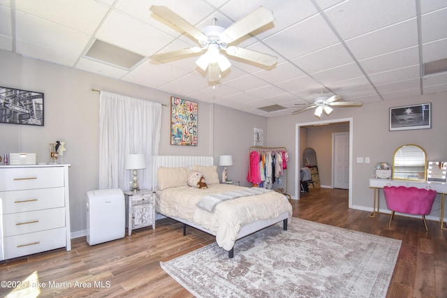 bedroom featuring a drop ceiling, baseboards, and wood finished floors