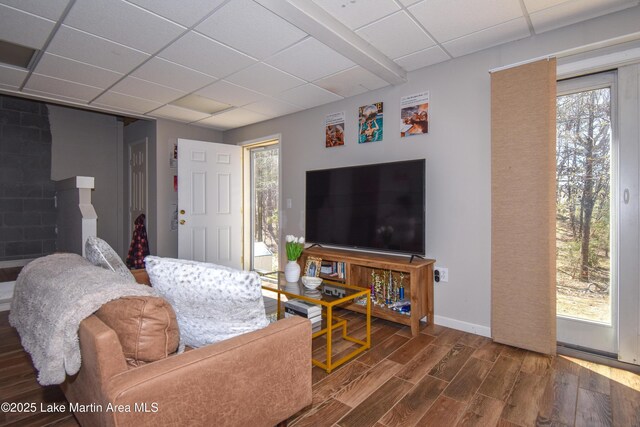 living room featuring a paneled ceiling, baseboards, and wood finished floors