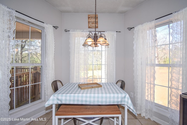 tiled dining area with a wealth of natural light, a textured ceiling, and an inviting chandelier