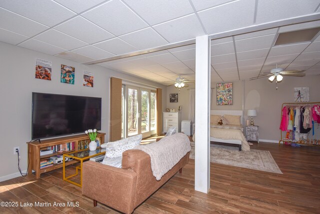 living room with a drop ceiling, baseboards, a ceiling fan, and wood finished floors