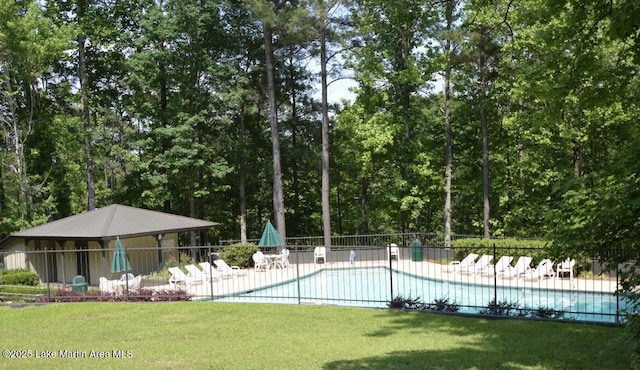 community pool with a patio area, fence, and a lawn