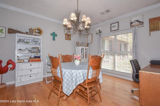 dining area with visible vents, baseboards, a chandelier, light wood-type flooring, and ornamental molding