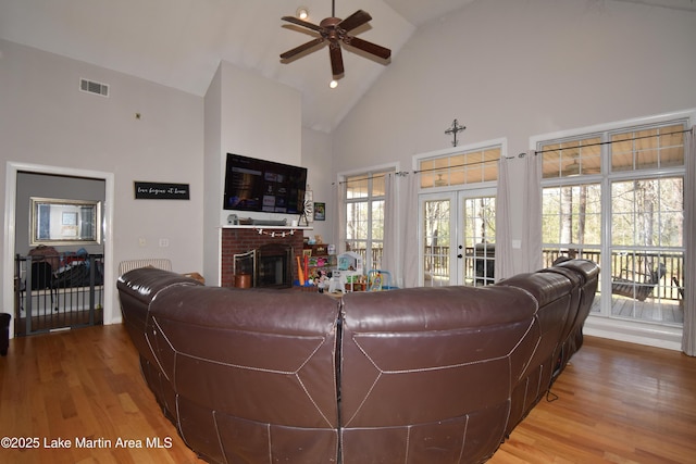 living room featuring visible vents, high vaulted ceiling, wood finished floors, a fireplace, and ceiling fan