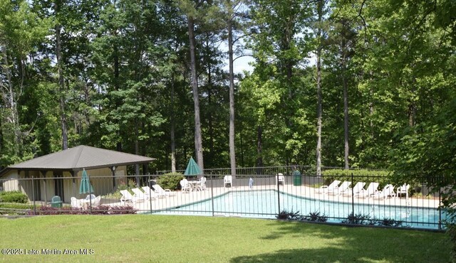 pool featuring a patio, a lawn, and fence