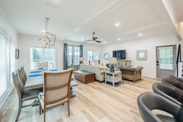 living room with a wealth of natural light, ceiling fan with notable chandelier, and light wood-type flooring