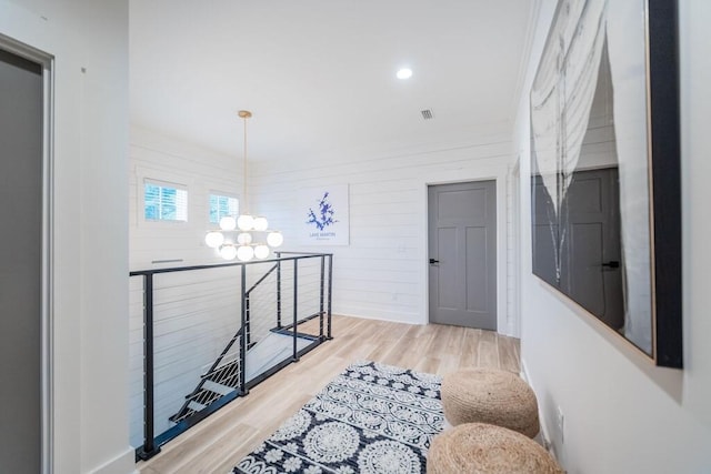 hallway featuring wood-type flooring and an inviting chandelier