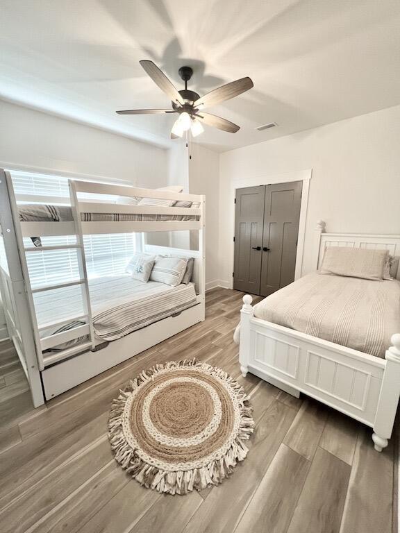 bedroom with wood-type flooring, a closet, and ceiling fan