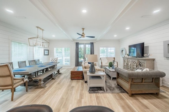 living room with beamed ceiling, ceiling fan with notable chandelier, and light hardwood / wood-style floors