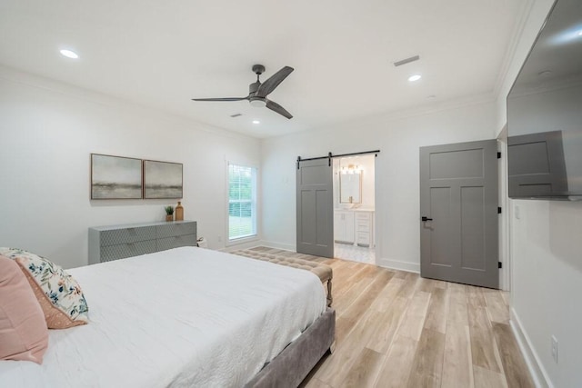 bedroom with ensuite bath, ceiling fan, a barn door, light hardwood / wood-style floors, and ornamental molding