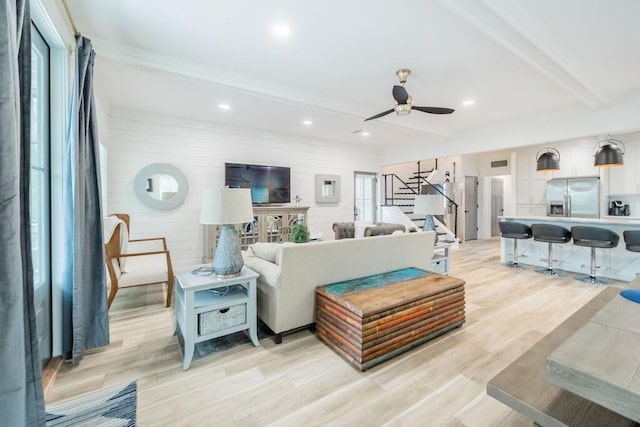 living room featuring beam ceiling, light hardwood / wood-style floors, and ceiling fan