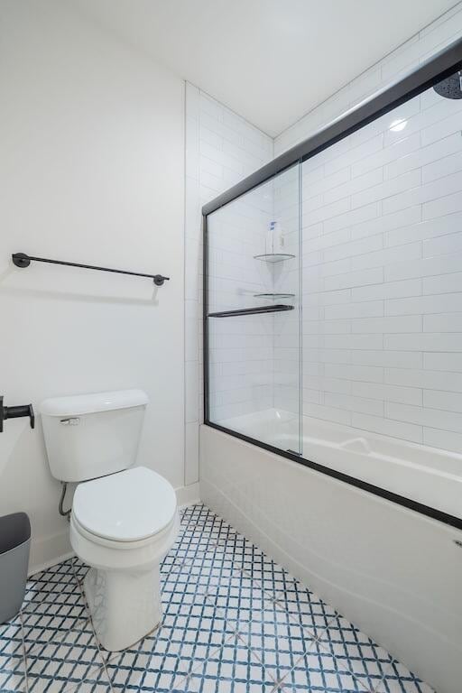 bathroom with toilet, tile patterned flooring, and combined bath / shower with glass door