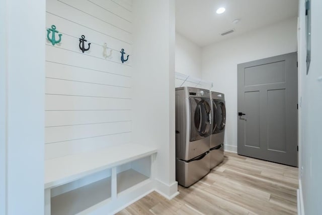 laundry area with washing machine and dryer and light wood-type flooring