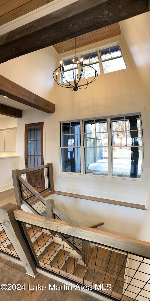 stairs with hardwood / wood-style flooring, high vaulted ceiling, a chandelier, a wealth of natural light, and beamed ceiling