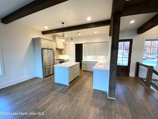 kitchen with sink, tasteful backsplash, hanging light fixtures, appliances with stainless steel finishes, and a kitchen island