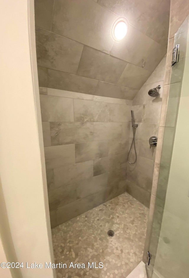 bathroom with lofted ceiling and tiled shower