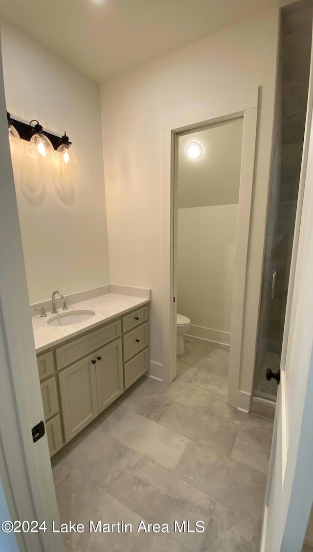 bathroom with vanity, toilet, and a shower with shower door