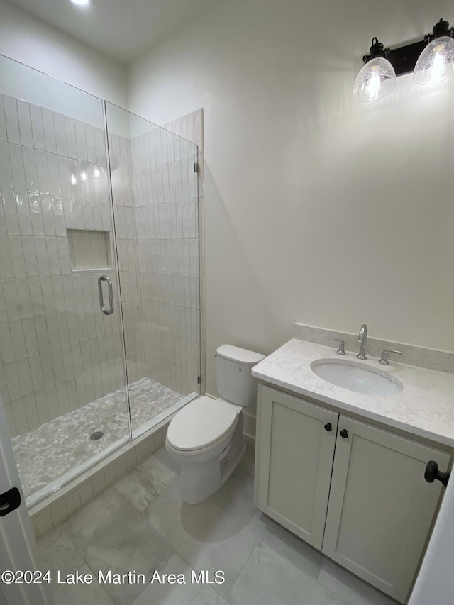 bathroom featuring vanity, toilet, and a shower with shower door