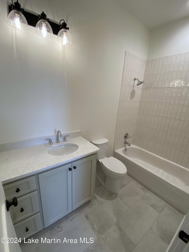 full bathroom featuring vanity, tiled shower / bath, and toilet