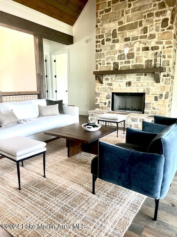 living room featuring lofted ceiling, hardwood / wood-style floors, wood ceiling, and a fireplace