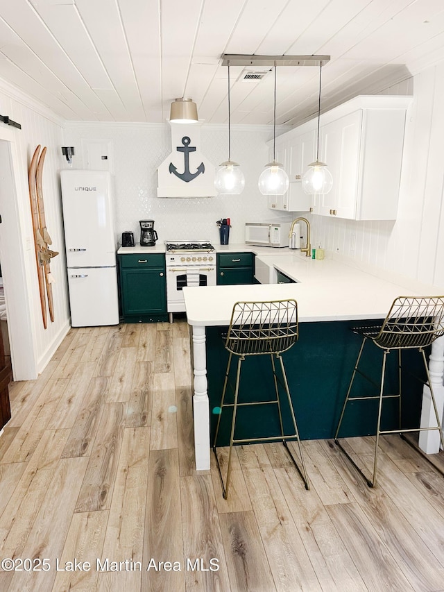 149 Lake Ridge Dr, Jacksons Gap, AL 36861 - kitchen featuring a breakfast bar, light wood-type flooring, white appliances, and a peninsula
