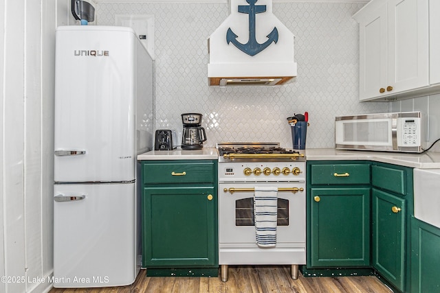 149 Lake Ridge Dr, Jacksons Gap, AL 36861 - kitchen with light countertops, premium range hood, white appliances, wood finished floors, and green cabinets
