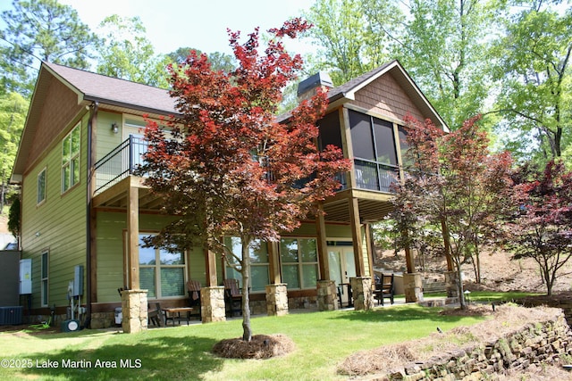 back of house featuring a sunroom, central air condition unit, a yard, and a chimney