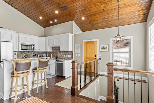 kitchen with white cabinets, decorative light fixtures, stainless steel appliances, and tasteful backsplash