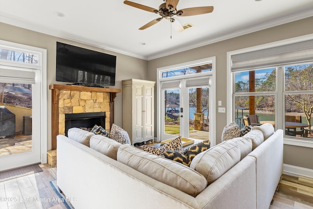 living room with visible vents, ornamental molding, a fireplace, french doors, and a ceiling fan
