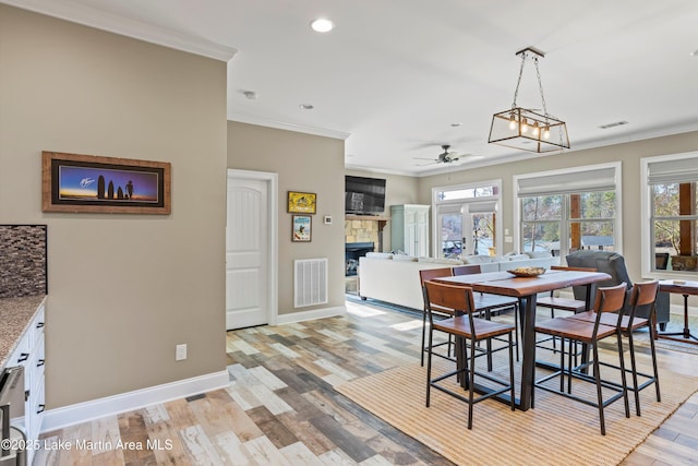 dining space with ceiling fan, a healthy amount of sunlight, light wood-type flooring, and crown molding