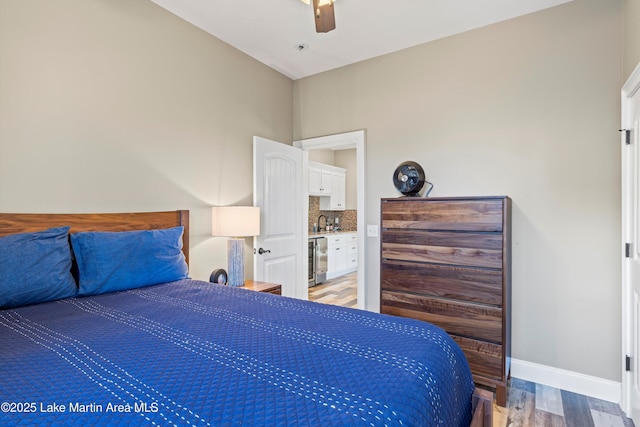 bedroom with ceiling fan, light wood finished floors, a sink, baseboards, and wine cooler