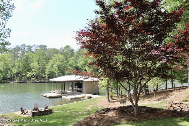 dock area with a yard, a water view, and a wooded view
