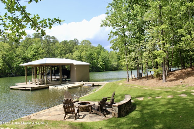 view of dock featuring a wooded view, a yard, a water view, and an outdoor fire pit