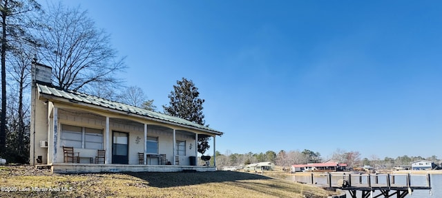 exterior space featuring a chimney, covered porch, and metal roof