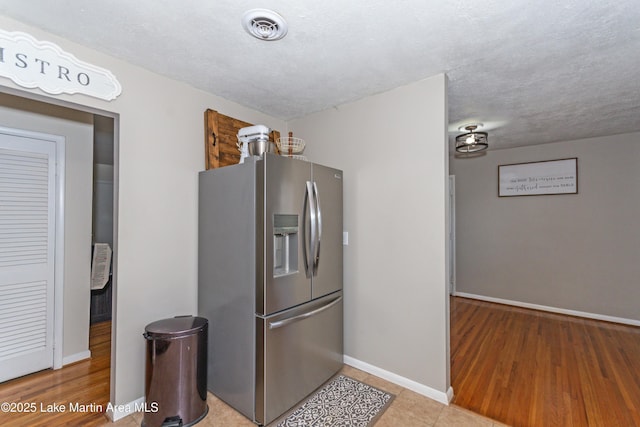 kitchen with stainless steel fridge and a textured ceiling