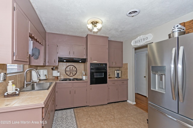 kitchen with sink, tasteful backsplash, a textured ceiling, tile counters, and black appliances