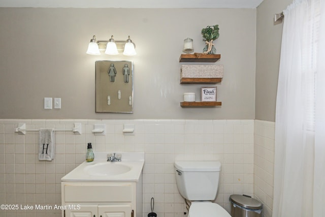 bathroom featuring vanity, tile walls, and toilet