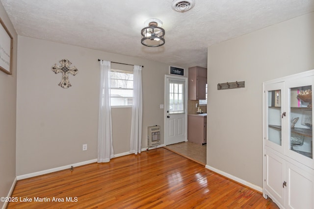 interior space featuring heating unit, light hardwood / wood-style floors, and a textured ceiling