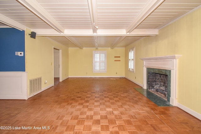 unfurnished living room with a premium fireplace, beamed ceiling, and light parquet floors