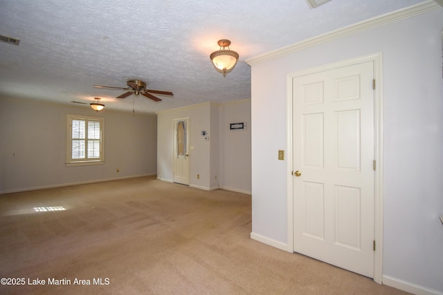 empty room featuring a textured ceiling, crown molding, light colored carpet, and ceiling fan