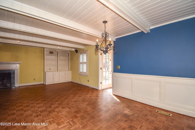 unfurnished dining area with a fireplace, beamed ceiling, parquet floors, and a notable chandelier