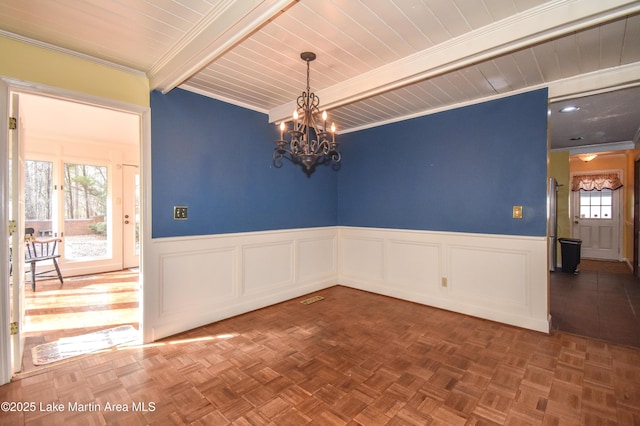 spare room featuring a wealth of natural light, beam ceiling, and parquet flooring